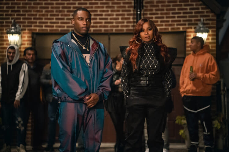 Cane (Woody McClain) in a shiny tracksuit and Monet standing and looking intense