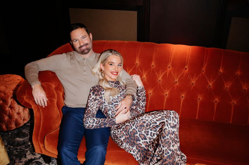 Helen Flanagan and Robbie Talbot sitting on a red sofa in a hotel