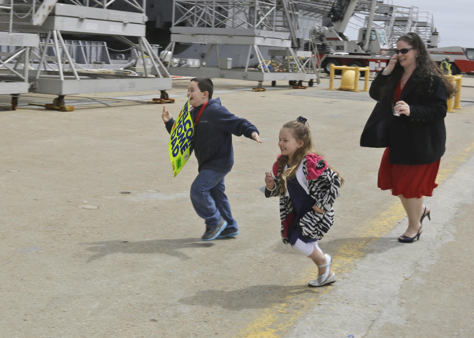 Austin Reifsnider, his sister Hailey, center, and mom Kristin, run to machinist mate Jonathan, Reifsnider, as he disembarks the nuclear aircraft carrier Harry S. Truman at Naval Station Norfolk in Norfolk, Va., Friday, April 18, 2014. The ship is returning to Norfolk after a 9-month deployment to the Middle East. (AP Photo/Steve Helber)