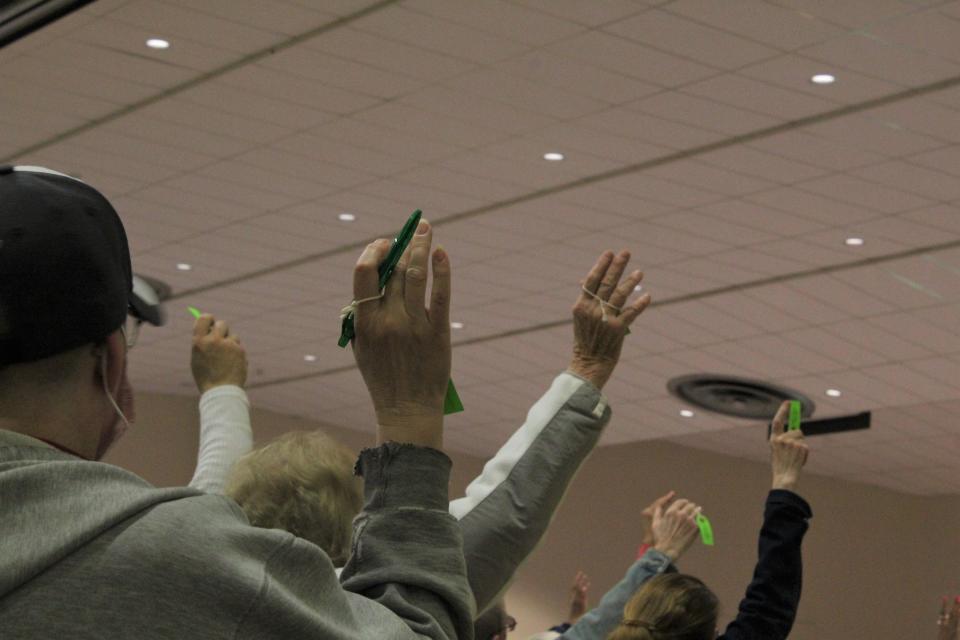 Voters raise their hands high for a count at the May 2022 town meeting in Dennis.