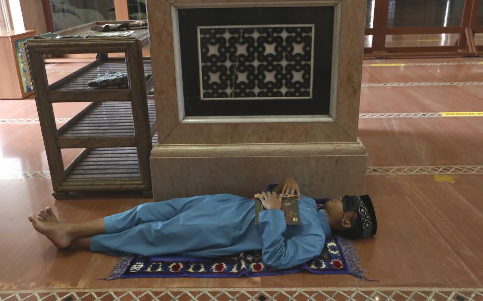 A man takes a nap while waiting for the time to break his fast at the Kubah Mas mosque in Depok, Indonesia, Friday, April 16, 2021. (AP Photo/Tatan Syuflana)