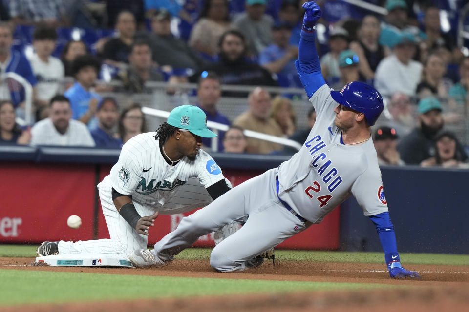 Chicago Cubs' Cody Bellinger (24) slides into third base as Miami Marlins third baseman Jean Segura (9) is late with the tag during the seventh inning of a baseball game, Friday, April 28, 2023, in Miami. (AP Photo/Marta Lavandier)
