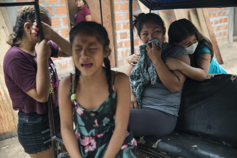 Family members mourn the passing of Manuela Chavez, who died from symptoms related to the new coronavirus at the age of 88, as a government team prepares to remove her body from inside her home, in the Shipibo Indigenous community of Pucallpa, in Peru's Ucayali region, Monday, Aug. 31, 2020. While the lucky are cured with ancestral ailments, the less fortunate often die at home. A government team travels from one spartan, thatch-roofed home to the next, removing the dead from their homes where they took their last breaths. (AP Photo/Rodrigo Abd)