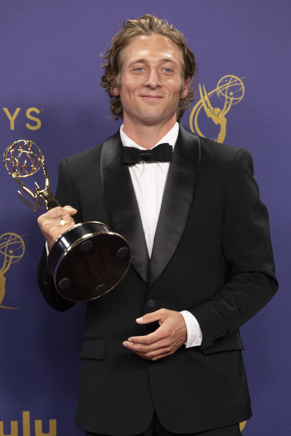 Jeremy Allen White in a black tuxedo holds an Emmy Award at a press event