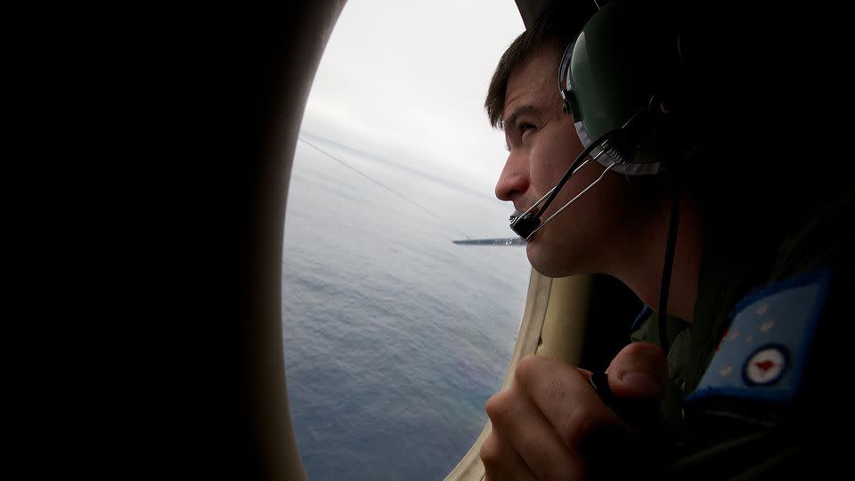 A crewman of an RAAF AP-3C Orion aircraft looking out his observation window whilst searching for missing Malaysia Airways Flight MH370, Monday, March 24, 2014. Source: AAP