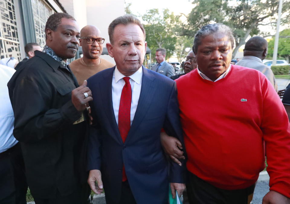 FILE- In this Jan. 11, 2019, file photo, suspended Broward County Sheriff Scott Israel, center, leaves a news conference surrounded by supporters in Fort Lauderdale, Fla., after new Florida Gov. Ron DeSantis suspended him, over his handling of last February's massacre at Marjory Stoneman Douglas High School. Before the shooting, Israel had changed his department's policy to say deputies "may" confront shooters from "shall," which critics say gave eight deputies who arrived during the shooting but stayed outside an excuse for not confronting the gunman. (AP Photo/Wilfredo Lee, File)