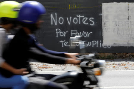 A motorcycle passes graffiti painted on a fence in Caracas, Venezuela May 12, 2018. Graffiti reads: "Do not vote, please I beg you". Picture taken on May 12, 2018. REUTERS/Carlos Jasso