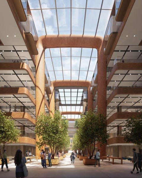A CGI rendering of a large office space with glass ceilings, red brick, and indoor trees.