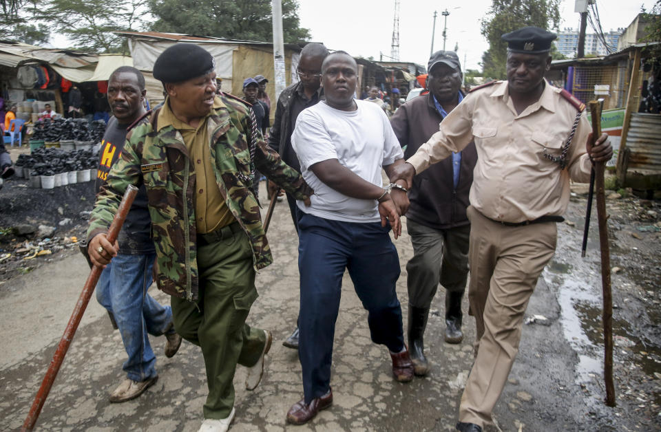 Security forces arrest a man for operating a restaurant serving food to customers eating on the premises, which has been prohibited and only takeaways are allowed under measures aimed at halting the spread of the new coronavirus, in Nairobi, Kenya Friday, March 27, 2020. The new coronavirus causes mild or moderate symptoms for most people, but for some, especially older adults and people with existing health problems, it can cause more severe illness or death. (AP Photo/Brian Inganga)