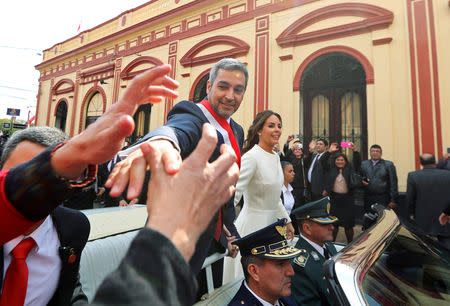 Paraguay's new President Mario Abdo Benitez is greeted by a supporter as he rides in an open car alongside Paraguay's first lady Silvana Lopez Moreira in Asuncion, Paraguay August 15, 2018. REUTERS/Marcos Brindicci