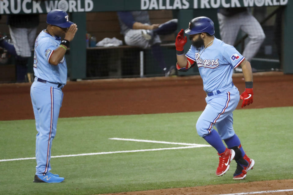 Texas Rangers' Rougned Odor, right, salutes with third base coach Tony Beasley, left, after hitting his second home run of the day in the fifth inning of a baseball game against the Houston Astros in Arlington, Texas, Sunday, Sept. 27, 2020. (AP Photo/Roger Steinman)