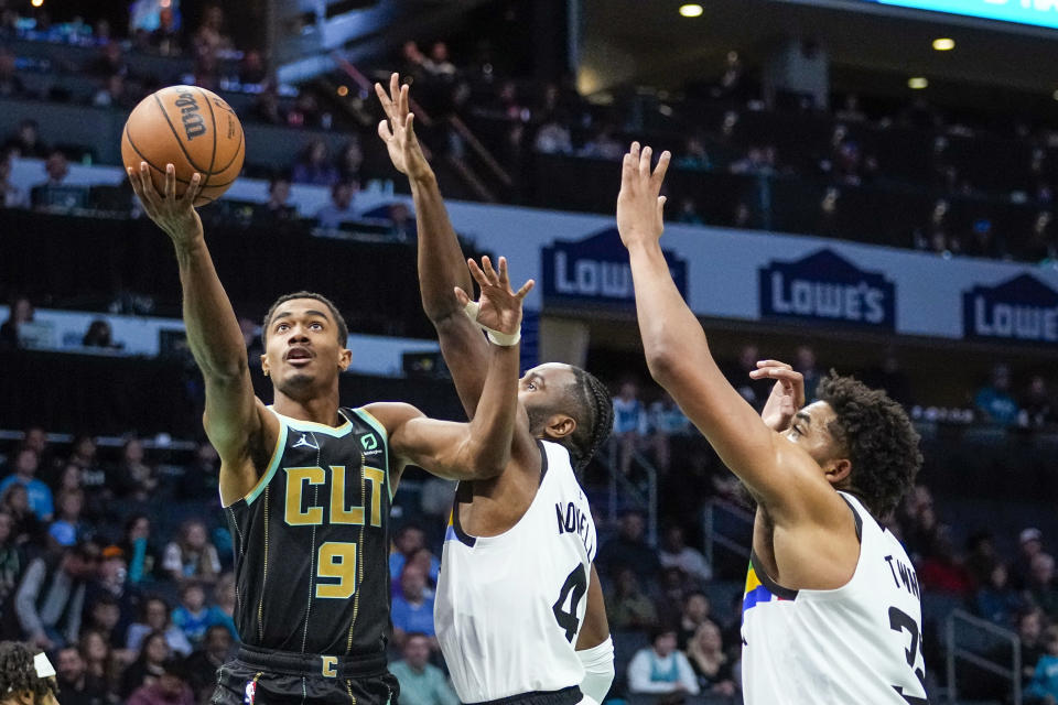 Charlotte Hornets guard Theo Maledon, left, shoots around Minnesota Timberwolves guard Jaylen Nowell, center, and center Karl-Anthony Towns during the first half of an NBA basketball game Friday, Nov. 25, 2022, in Charlotte, N.C. (AP Photo/Rusty Jones)