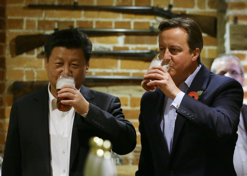 FILE - In this Thursday, Oct. 22, 2015 file photo, Britain's Prime Minister David Cameron, right, drinks beer with Chinese President Xi Jinping, at a pub in Princess Risborough, near Chequers, England. Only five years ago, former British Prime Minister David Cameron was celebrating a “golden era” in U.K.-China relations, bonding with President Xi Jinping over a pint of beer at the pub and signing off trade deals worth billions. Those friendly scenes now seem like a distant memory, with hostile rhetoric ratcheting up this week over Beijing’s new national security law on Hong Kong. China has threatened “consequences” after Britain offered refuge to millions in the former colony. (AP Photo/Kirsty Wigglesworth, file)