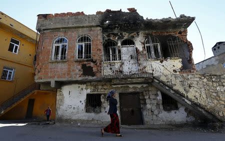 A woman walks past a building which was damaged during the security operations and clashes between Turkish security forces and Kurdish militants, in the southeastern town of Silvan in Diyarbakir province, Turkey, December 7, 2015. REUTERS/Murad Sezer