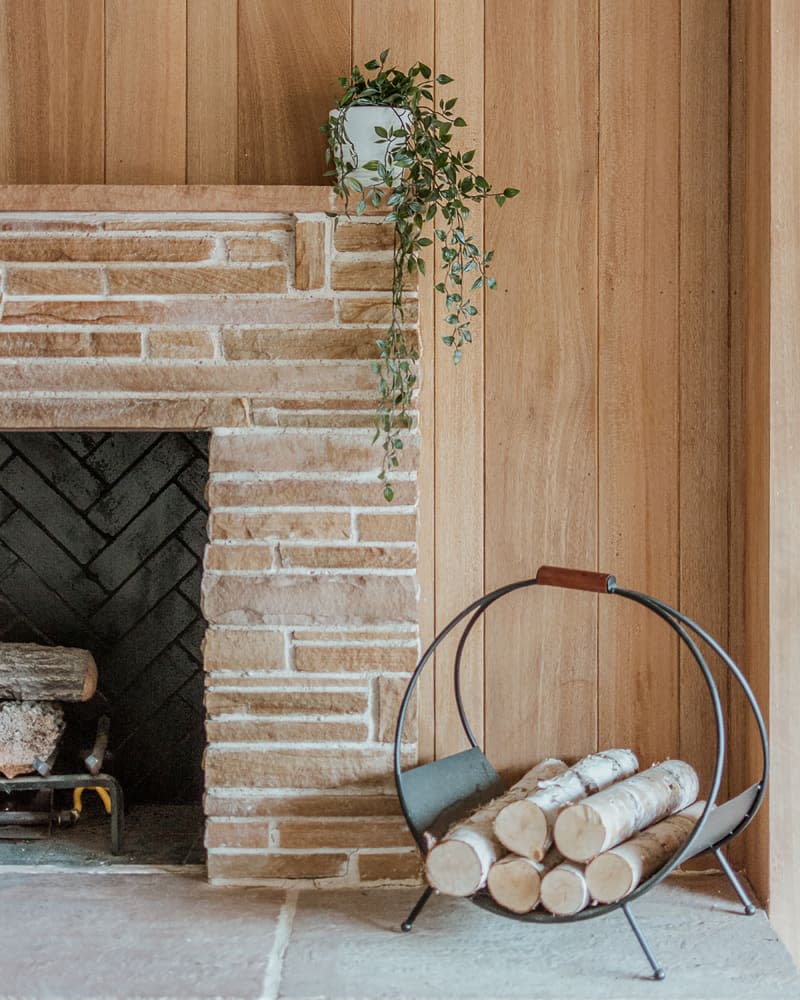 Wood in holder next to fireplace.