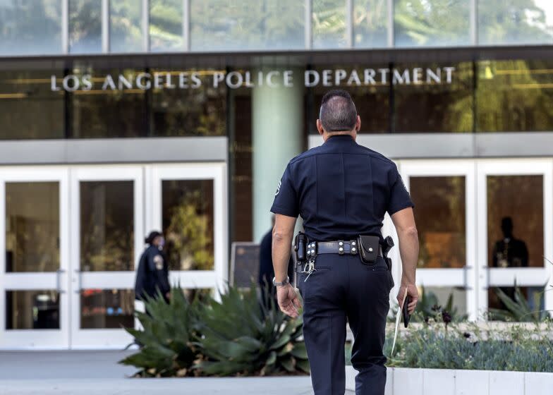 LOS ANGELES, CA - OCTOBER 14, 2021: A member of the LAPD makes his way into their headquarters on 1st St. in downtown Los Angeles. Los Angeles will officially require its city workers to be vaccinated against COVID-19 as the vaccination and reporting rules become "conditions of city employment," according to its ordinance. But it remains unclear what will happen to those who have refused to get the shots. (Mel Melcon / Los Angeles Times)