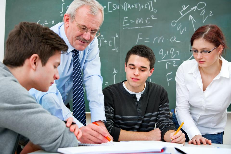 Students in maths class. Teacher showing them something.