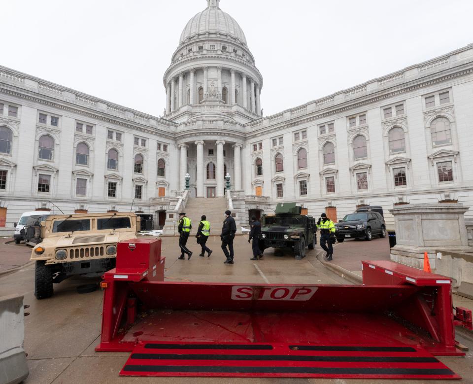 Law enforcement personnel walk past Wisconsin National Guard vehicles and a barricade on Sunday at the Wisconsin State Capitol in Madison.