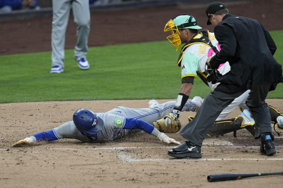 Toronto Blue Jays' Cavan Biggio, left, slides in to score off a two-RBI double by Kevin Kiermaier as San Diego Padres catcher Kyle Higashioka, center, is late with the tag during the second inning of a baseball game, Friday, April 19, 2024, in San Diego. (AP Photo/Gregory Bull)