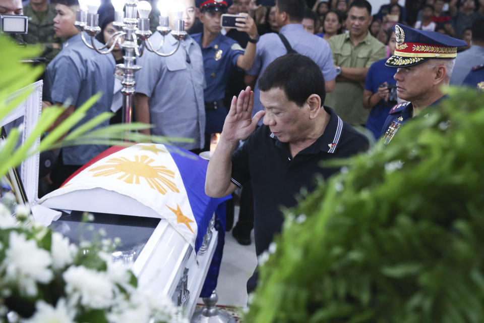 In this photo provided by the Presidential Malacanang Palace on Saturday July 20, 2019, Philippine President Rodrigo Duterte salutes to pay his last respects to one of the slain police officers during his visit to their wake at Camp Lt. Col. Francisco C. Fernandez Jr. in Sibulan, Negros Oriental, in Central Philippines. On Thursday, July 25, 2019, President Rodrigo Duterte said he raised a reward of 3 million pesos ($59,000) out of anger for what he described as the Islamic State group-style killings of the officers on July 18 in Negros Oriental province. Communist guerrillas claimed responsibility for the attack but denied torturing the police officers. (Ace Morandante/Presidential Photo Via AP)