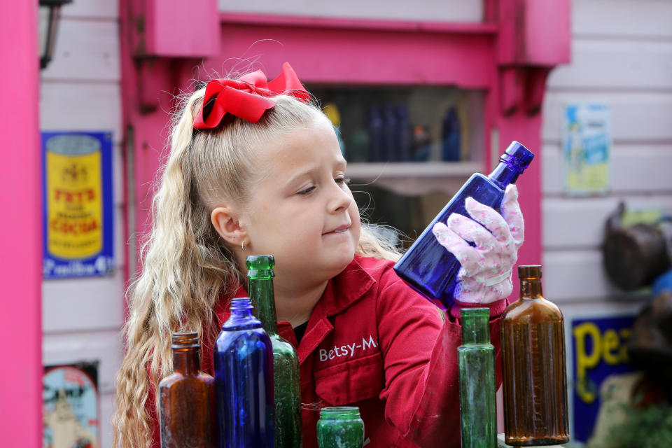 A seven-year-old schoolgirl is raking in hundreds of pounds by selling antique bottles from a little shop in her back garden - after digging them up from old landfill sites. Betsy-Mae Lloyd has been coining it in after launching her own business at her parents' home while still attending primary school.  The young entrepreneur flogs old bottles, jars and teapots - dating back to between the 1870s and 1930 - which she finds on historic landfill sites in the West Midlands.  After taking them home and cleaning them up herself, she then stores them in a Victorian-style play shed, built by dad Jason, before listing them for sale on Facebook. 