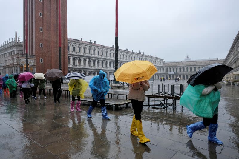 FILE PHOTO: People walk in St. Mark's Square during exceptional high tide as the flood barriers known as Mose are raised, in Venice