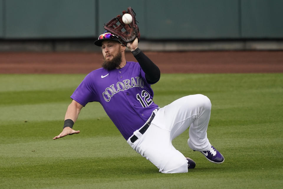 Colorado Rockies' Chris Owings catches a fly out hit by Seattle Mariners' Julio RodrÃ­guez during the second inning of a spring training baseball game, Saturday, March 13, 2021, in Scottsdale, Ariz. (AP Photo/Matt York)