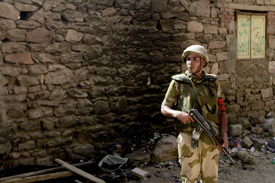 A military soldier stands guard as Egyptian prosecutor general, Hisham Barakat, tours the area where fighting took place on Friday, April 4, between a Nubian family and members of the Arab Haleyla clan, in the southern city of Aswan, Egypt, Tuesday, April 8, 2014. Telephone and Internet networks were briefly shut down to Egypt’s southern province of Aswan for several hours, as authorities moved to try to end a bloody tribal feud that killed tens the past week, security officials and residents said Tuesday. (AP Photo/Sabry Khaled, El Shorouk Newspaper) EGYPT OUT