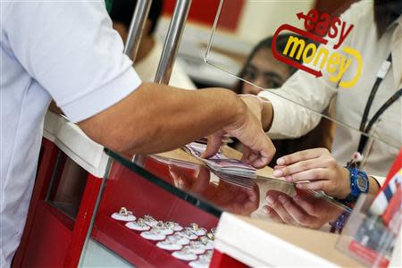 A customer gets money after selling his items at Easy Money pawn shop in Bangkok, August 27, 2013. REUTERS/Athit Perawongmetha