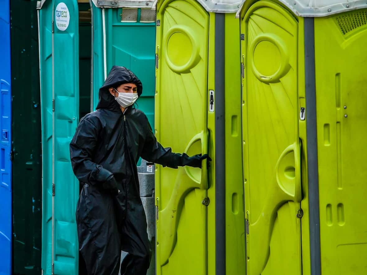 A woman wearing a protective suit uses a public toilet in Bogota in August 2020, amid the COVID-19 pandemic.  (Juan Barreto/AFP/Getty Images - image credit)