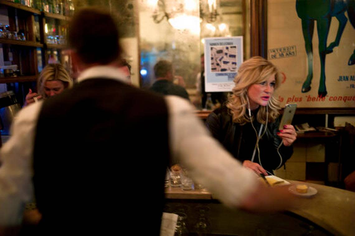 A customer uses her cellphone as she sits in a Paris cafe in 2019.