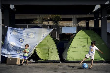 Two children play with a ball at a makeshift camp for refugees and migrants at the port of Piraeus, near Athens, Greece, April 20, 2016. REUTERS/Michalis Karagiannis