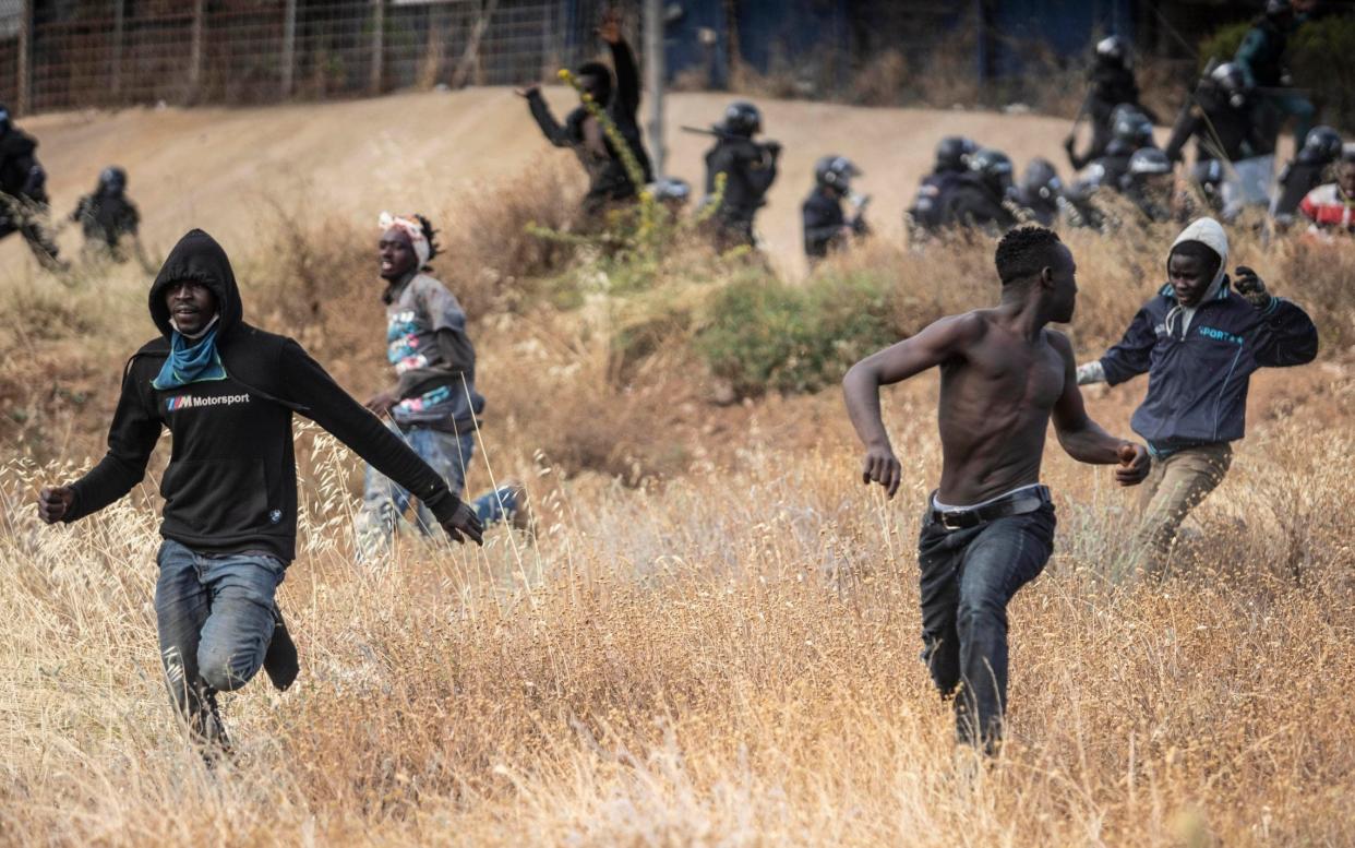 Migrants run on Spanish soil after crossing the fences separating the Spanish enclave of Melilla from Morocco on June 24 - Javier Bernardo/AP