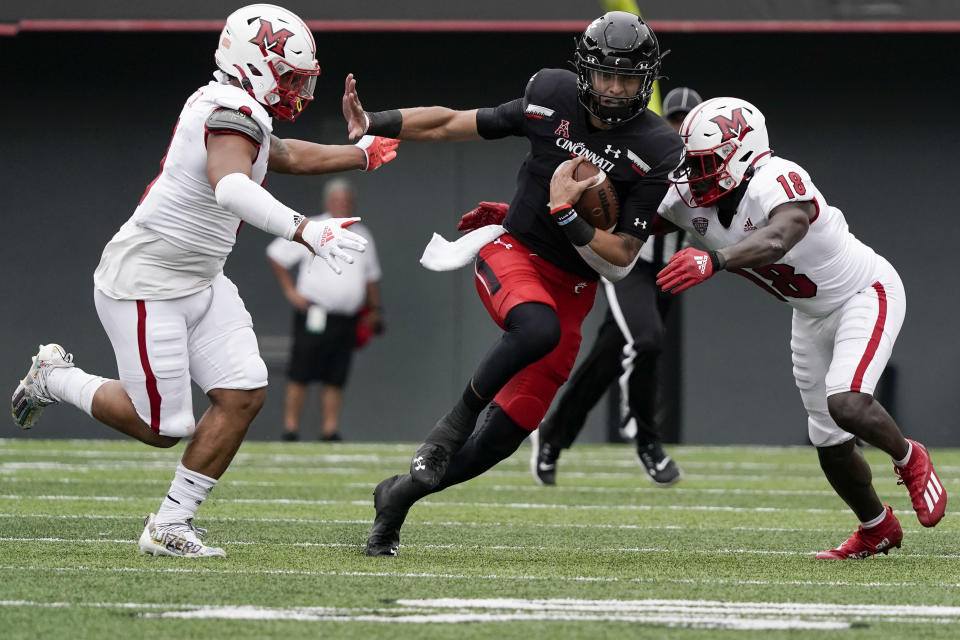 Cincinnati quarterback Desmond Ridder, center, runs the football during the first half an NCAA college football game against Miami (Ohio), Saturday, Sept. 4, 2021, in Cincinnati. (AP Photo/Jeff Dean)