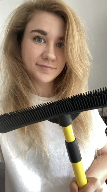 BuzzFeed editor holding broom with black silicone bristles 