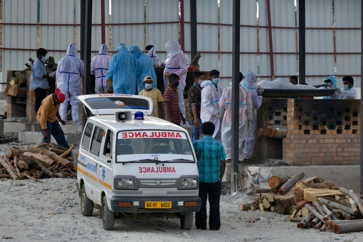 Family members and undertakers carry the body of a victim who died of COVID-19 at an open-air crematorium set up for coronavirus victims inside a defunct granite quarry on the outskirts of Bangalore on May 8, 2021, as India recorded more than 4,000 coronavirus deaths in a day for the first time.