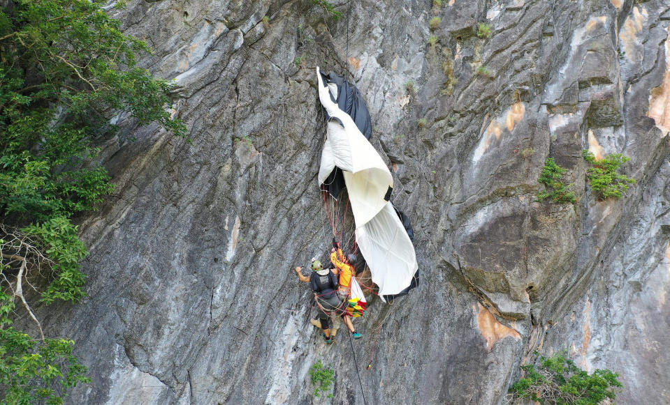 In this image released by the Phattalung Rescue Organization, a base jumper is rescued after his parachute was caught on a rock's edge, Monday, Jan. 13, 2020, in Phattalung, Thailand. An Austrian base jumper, Johannes Grasser, 28, was rescued in southern the Thai province after being stuck on a near vertical cliff for hours when his parachute caught a rock’s edge, almost 200 meters (656 feet) above the around. (Phattalung Rescue Organization via AP)