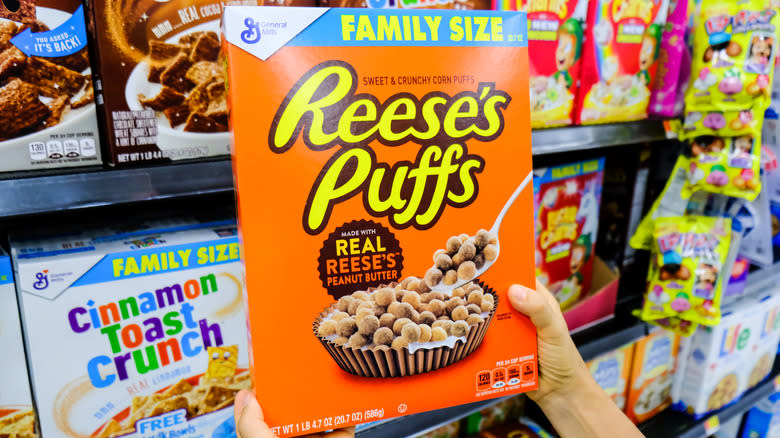 holding up box of reese's puffs in cereal aisle