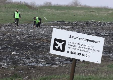 Investigators work near a sign reading "No entrance! There may be remains of the victims of flight MH17 crash at the territory" at the site of the Malaysia Airlines Boeing 777 plane crash near the village of Hrabove (Grabovo) in Donetsk region, April 16, 2015. REUTERS/Igor Tkachenko