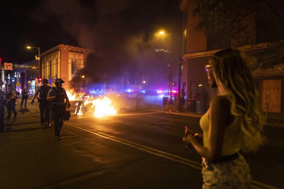 Police stand guard after protesters set fire to dumpsters on the street after a vigil was held for Winston Boogie Smith Jr. early on Saturday, June 5, 2021. Smith was shot and killed by law enforcement officers on Thursday during an arrest warrant operation. (AP Photo/Christian Monterrosa)