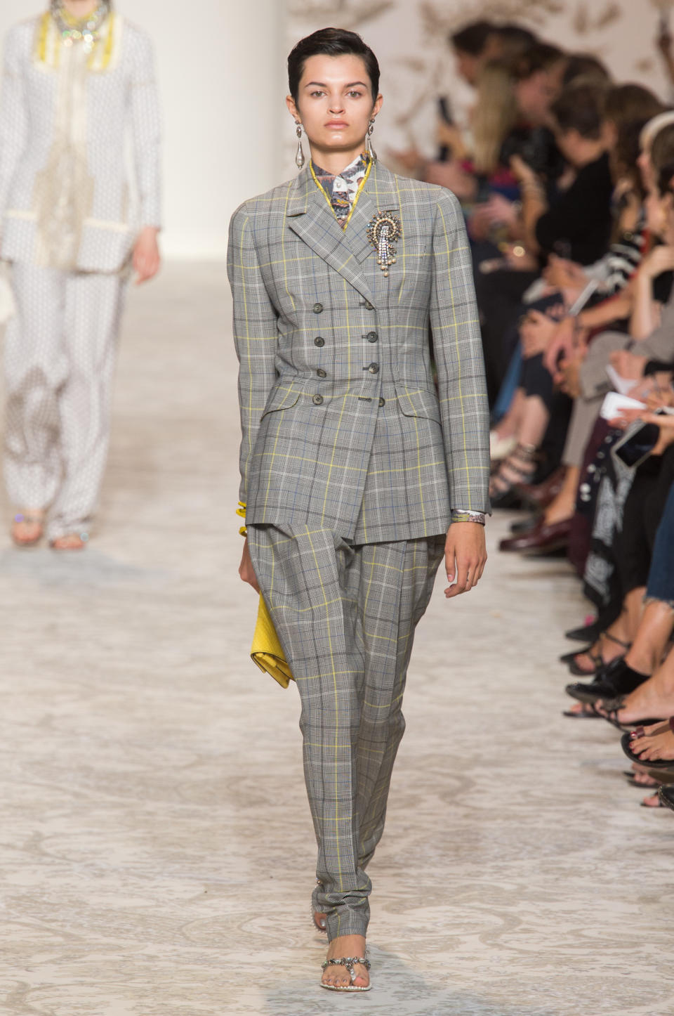 <p><i>Model wears a gray and yellow plaid suit with statement brooch and earrings from the SS18 Etro collection. (Photo: ImaxTree) </i></p>
