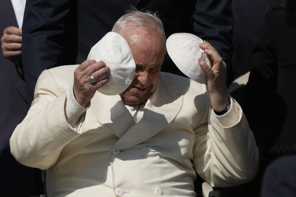 Pope Francis exchanges his skull cap with one presented by a participant in the weekly general audience in St. Peter's Square, at the Vatican, Wednesday, April 19, 2023. (AP Photo/Alessandra Tarantino)