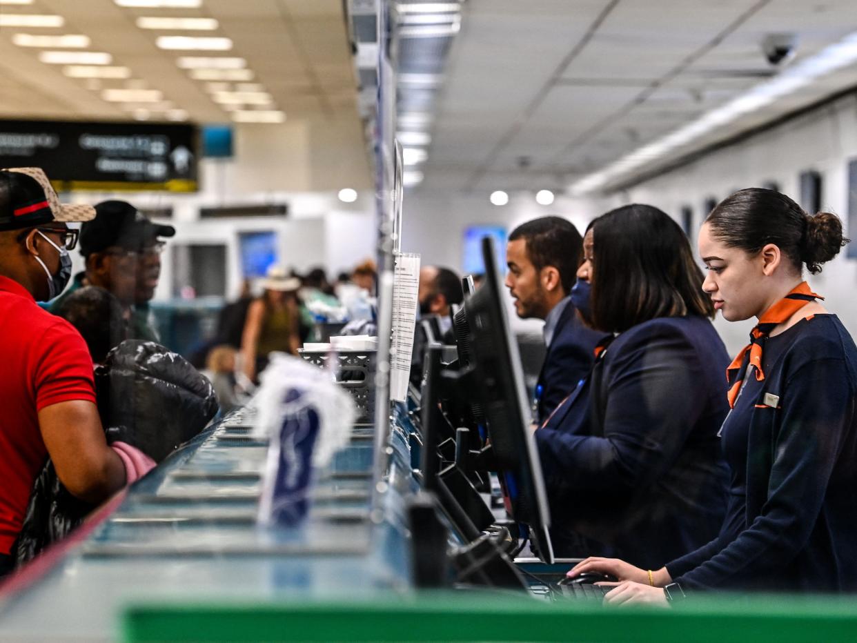 Airline employees with and without face masks work at Miami International Airport after a ruling by federal judge ended mask mandates on public transportation.