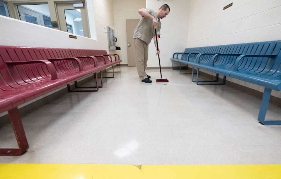 Robert Carpenter, an inmate at the Stark County Jail, sweeps the prisoner release area.