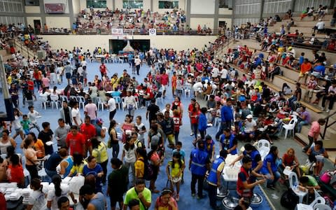 Evacuees seek temporary shelter at an evacuation center after fleeing their homes following the deadly landslide - Credit: Bullit Marquez/AP