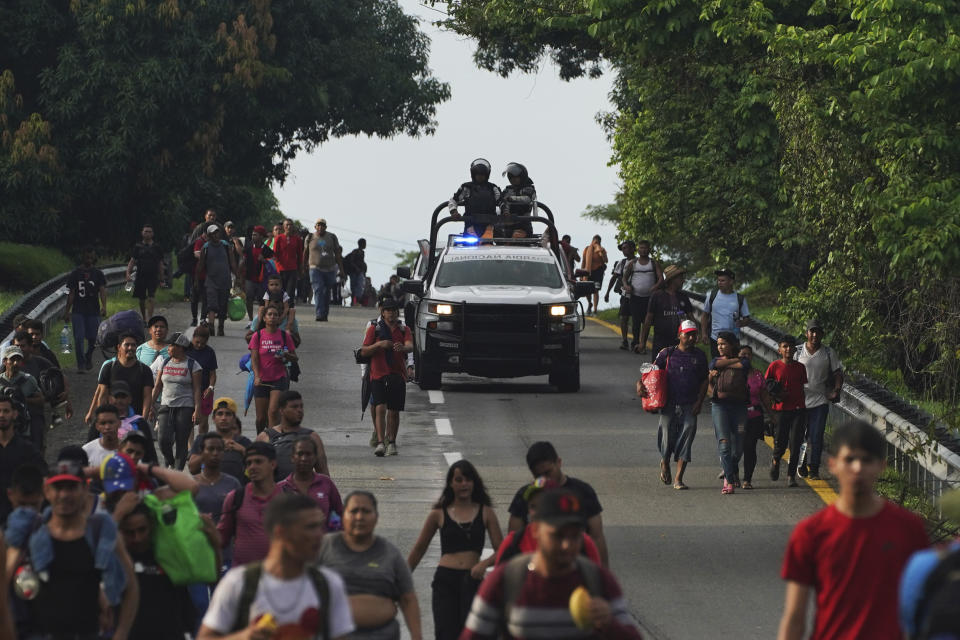 Miembros de la Guardia Nacional avanzan junto a migrantes por la carretera hacia la salida a Huixtla, estado de Chiapas, México, la madrugada del jueves 9 de junio de 2022. El grupo de migrantes salió de Tapachula el lunes, cansado de esperar para normalizar su estatus en una región con poco trabajo, con el objetivo de llegar a Estados Unidos (AP Foto/Marco Ugarte)