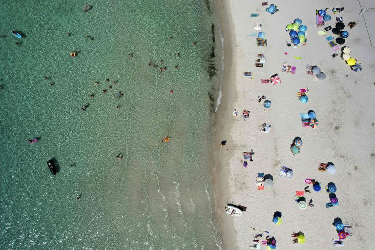En esta foto de archivo tomada el 17 de julio de 2022, una vista aérea muestra a turistas en la playa Mare e Sole en Pietrosella, en la isla mediterránea francesa de Córcega.