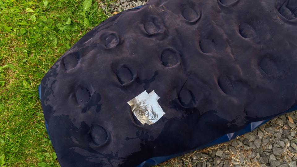 An air mattress with a hole that's been patched up with duct tape
