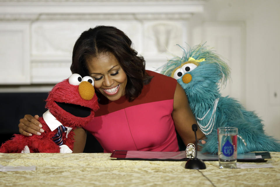 First lady Michelle Obama, center, with PBS Sesame Street's characters Elmo, left, and Rosita, right, as they help promote fresh fruit and vegetable consumption to kids in an event in the State Dining Room of the White House in Washington, Wednesday, Oct. 30, 2013. Sesame Workshop and the Produce Marketing Association (PMA) joined in Partnership for a Healthier America (PHA) in announcing a 2-year agreement to making healthy choices by using the Sesame Street characters to help deliver the messages about fresh fruits and vegetables. (AP Photo/Pablo Martinez Monsivais)