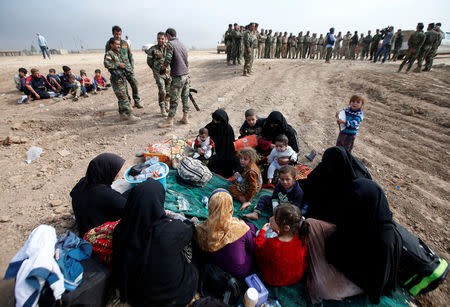 Displaced Iraqi women and children sit near Kurdish Peshmerga fighters after escaping from the Islamic State-controlled village of Abu Jarboa, Iraq October 31, 2016. REUTERS/Azad Lashkari